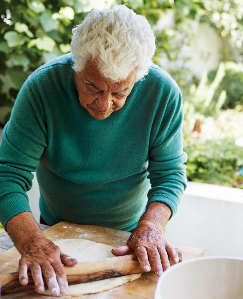 Antonio Carluccio carefully rolling some dough on a wooden board using a simple wooden rolling pin