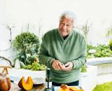 Antonio Carluccio standing at a table in his garden, holding a bulb of garlic, slices of pumpkin on a tray in front of him